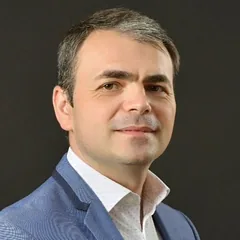 Adi Ploscaru, fondatorul PerformanceX, în sacou albastru, pe fundal închis.